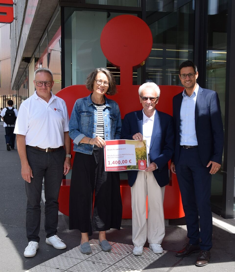 Scheckübergabe Vier Personen vor der Sparkasse bei Scheckübergabe